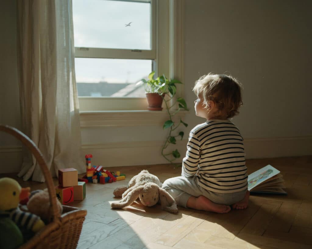 Child sitting at a window illustrating childhood attachment and developmental trauma